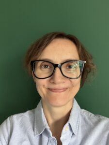 Beata Palińska, uśmiechnięta brunetka po 40tce w okularach i błękitnej koszuli